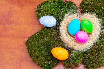 Fototapeta na wymiar Multi-colored Easter eggs on a green moss on wood background