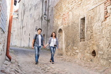 Obraz na płótnie Canvas Young travelling couple having a medieval walk on an old street with tile road.