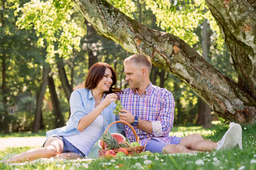 Beautiful couple having a lovely picnic in the summer park