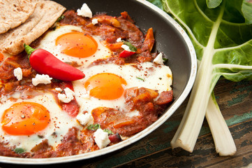 Shakshuka, a dish of eggs poached in a sauce of tomatoes, chili peppers, and onions, spiced with cumin. This recipe includes swiss chard leaves. Tunisian origin but is also very popular in Israel.