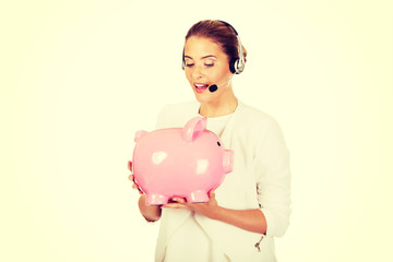 Fototapeta na wymiar Young businesswoman in headset holding piggybank