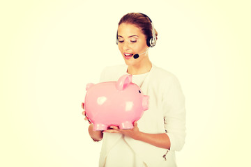 Young businesswoman in headset holding piggybank