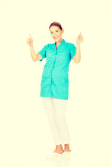 Smile young female doctor or nurse with thumbs up