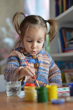Little girl drawing with paints