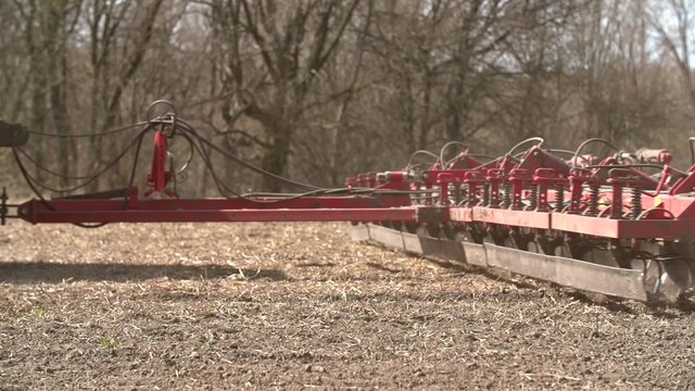 Close up of a tractor seeding, plowing and cultivating the field in the spring.  Agriculture concept. Tracking shot. Slow Motion.