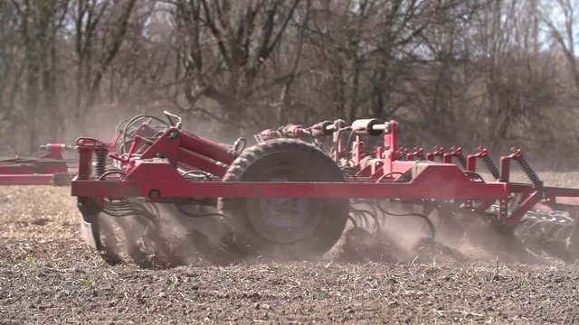 Close up of a tractor seeding, plowing and cultivating the field in the spring.  Agriculture concept. Tracking shot. Slow Motion.