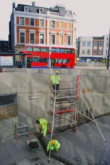 Foto op Plexiglas Scene from Finsbury Park, London with red bus and people in uniforms at work using scaffolding © Savo Ilic