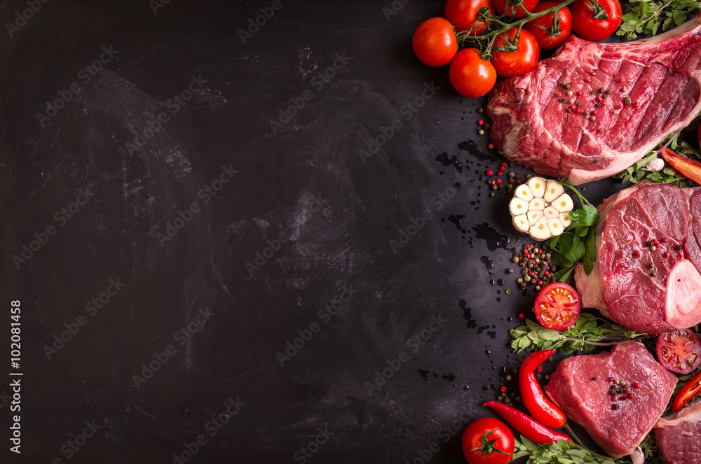 Wall mural raw meat steaks on a dark background ready to roasting