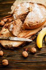 
pastries, cake with walnuts and a banana with powdered sugar on a wooden background