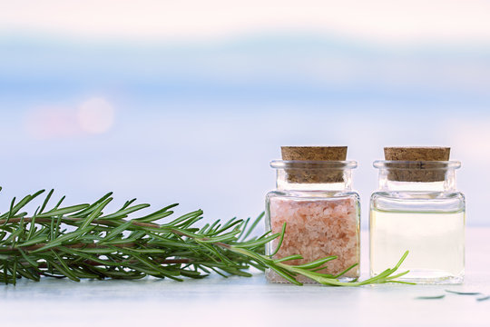 Rosemary aromatherapy essential oil and salt in bottles on sunset