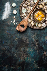 Quail eggs with cooking spoon on rustic background, top view. Broken quail egg.