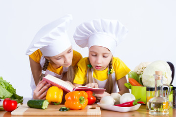 two girls looking for a recipe in the book