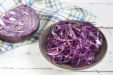 Fototapeta premium Sliced red cabbage in clay bowl on white wooden table