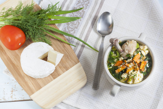 Cheese soup with chicken, herbs and vegetable. Camembert, tomato and herbs on wooden board. Light background