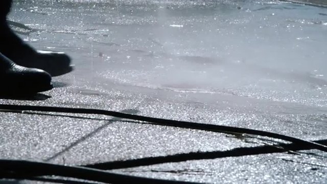 teenage boy power washing a dirty residential driveway as a summertime job.