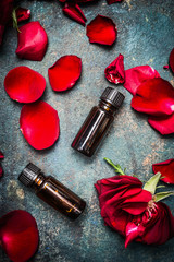 Obraz na płótnie Canvas Roses essential oil in dark bottle on rustic background, top view. Cosmetic , aromatherapy , spa or wellness concept.