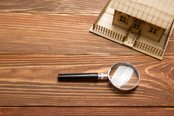 Real Estate Concept. Model house and magnifying glass on wooden table. Top view.