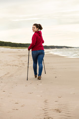 Nordic walking - young woman working out on beach 