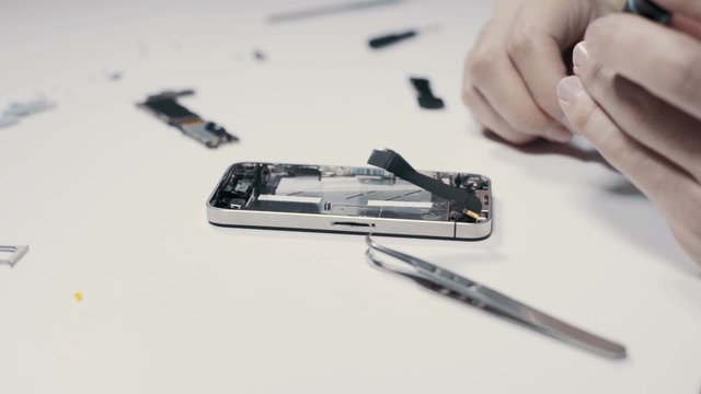 Smart phone repairing with tweezers at service center, close up