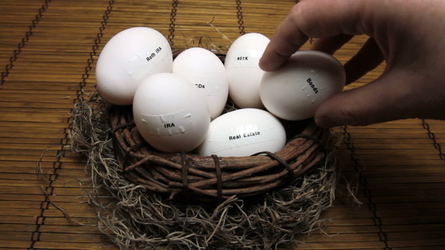 Hand removing eggs labeled with retirement assets from nest.

