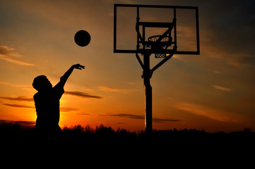 Fototapeta premium Silhouette of Teen Boy shooting a Basketball