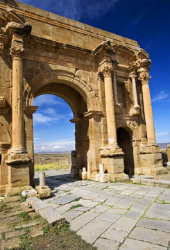 Algeria. Timgad (ancient Thamugadi or Thamugas). Triumphal arch, called Trajan's Arch (Corinthian order with three arches) and paving stones of Decumanus Maximus street