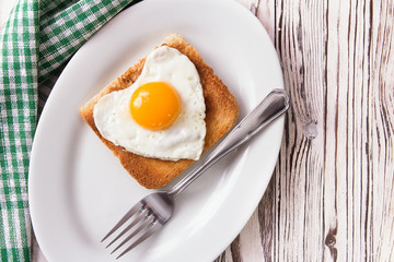 Fried egg on bread for breakfast on plate and rustic table