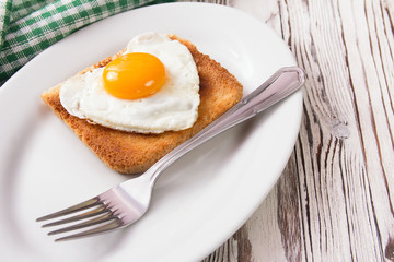 Fried egg on bread for breakfast on plate and rustic table