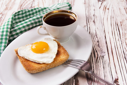 Fried egg on bread for breakfast on plate and rustic table