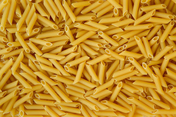 Uncooked Penne pasta on white background
