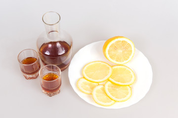 The decanter of brandy, wine glasses and sliced lemons on a white background, appetizer for alcohol, meeting old friends,