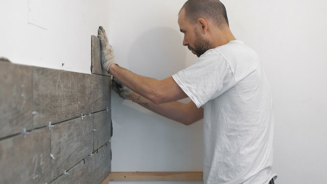 Home improvement, renovation - construction worker tiler is tiling, ceramic tile wall adhesive, trowel with mortar