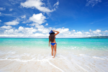 Enjoying freedom. Beautiful woman on beach in summer hat