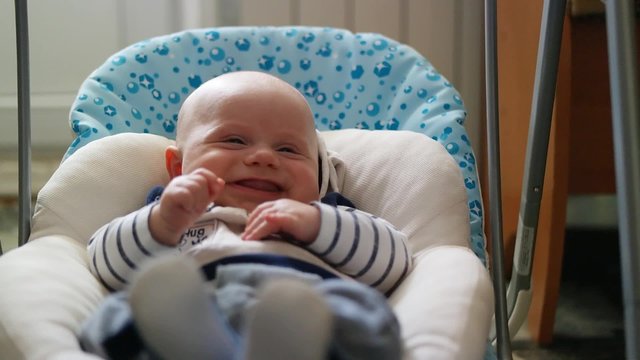 Happy little cute baby girl swing in electric swing at living room. 