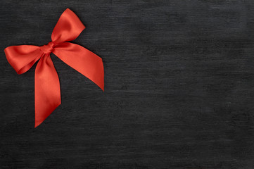 Red satin ribbon with bow isolated over black background.