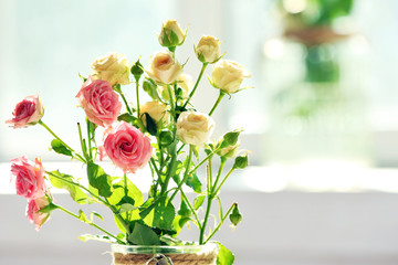 Beautiful spring flowers in vase on window background