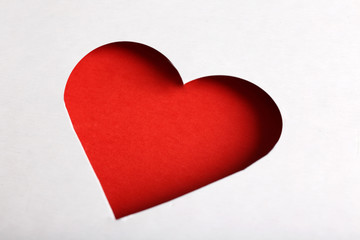 Cut out white paper heart on red background