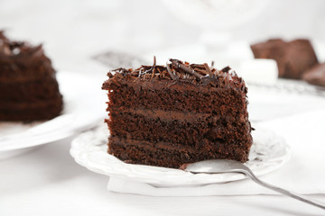 Sliced chocolate cake on wooden table, on light background