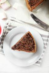 Sliced chocolate cake on plate, on wooden table  background