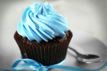 Delicious chocolate cupcake with blue cream on decorated wooden  table, close up