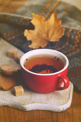 Cup of tea with autumn decor on wooden table.