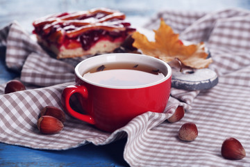 Cup of tea with autumn decor on wooden table.