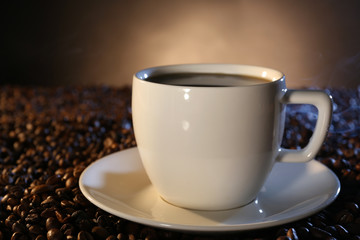 Cup of hot coffee among coffee beans on dark background