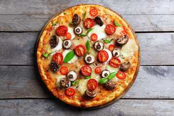 Tasty fresh pizza decorated with mushrooms and tomatoes on wooden background, close up