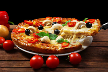 Delicious pizza and fresh vegetables on wooden background, close up