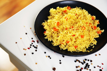 Stewed rice with a carrot on a black plate