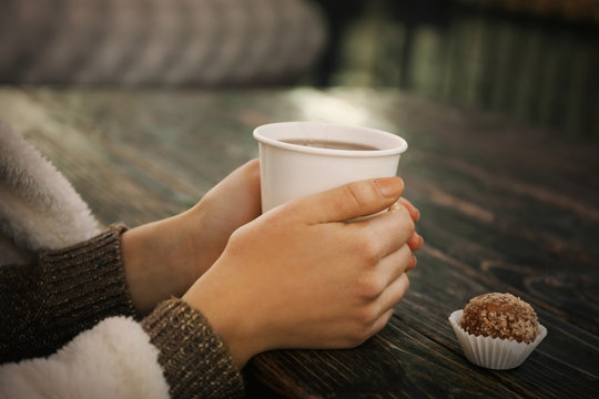 Female hands holding a cup of hot drink at the table