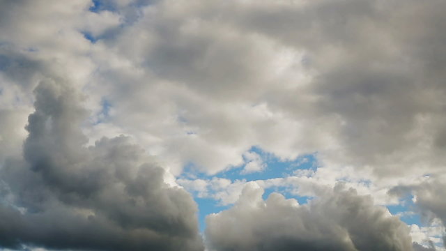 Thick, puffy cumulus clouds roll over a blue sky in time lapse fashion. 60 second loop.