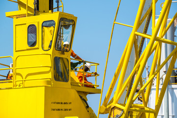 Men working at yellow crane with blue sky