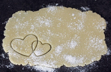 Two crossed hearts on dough layer flour powdered